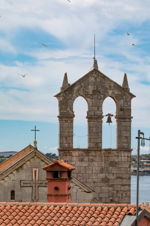 a clock tower on top of a building next to a body of water, romanesque, hosada, flying buttresses, seaview, rust