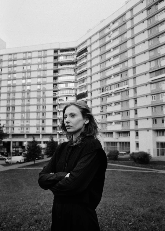 a woman standing in front of a tall building, a black and white photo, olya bossak, suburban, thom yorke, series
