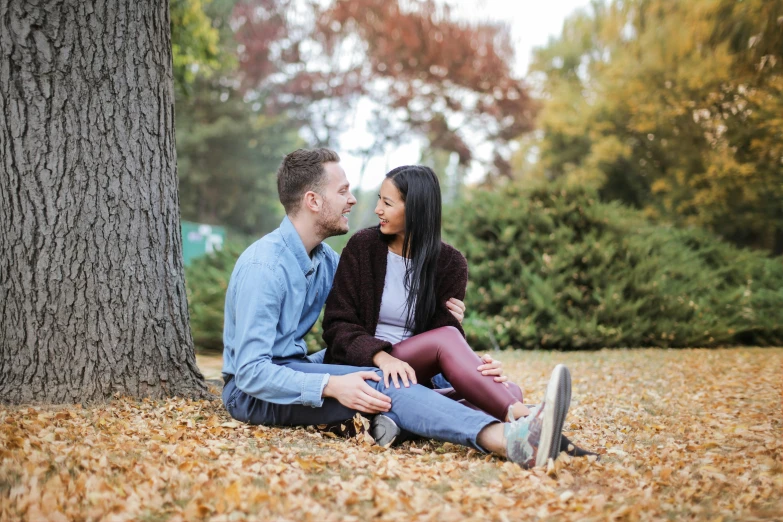 a man and woman sitting on the ground next to a tree, pexels contest winner, autumn colours, profile image, thumbnail, sydney park