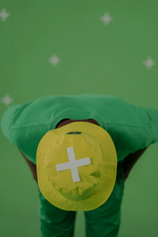 a person wearing a hat with a cross on it, happening, green and yellow, zoomed out shot, tv commercial, maths