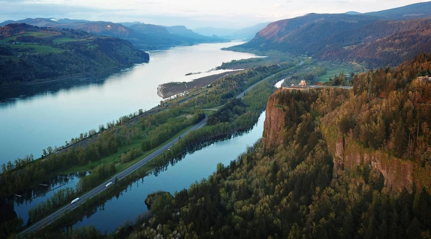 a river running through a valley next to a forest, by Jim Nelson, pexels contest winner, hudson river school, sharp cliffs, aerial view of an ancient land, puyallup berteronian, wide river and lake