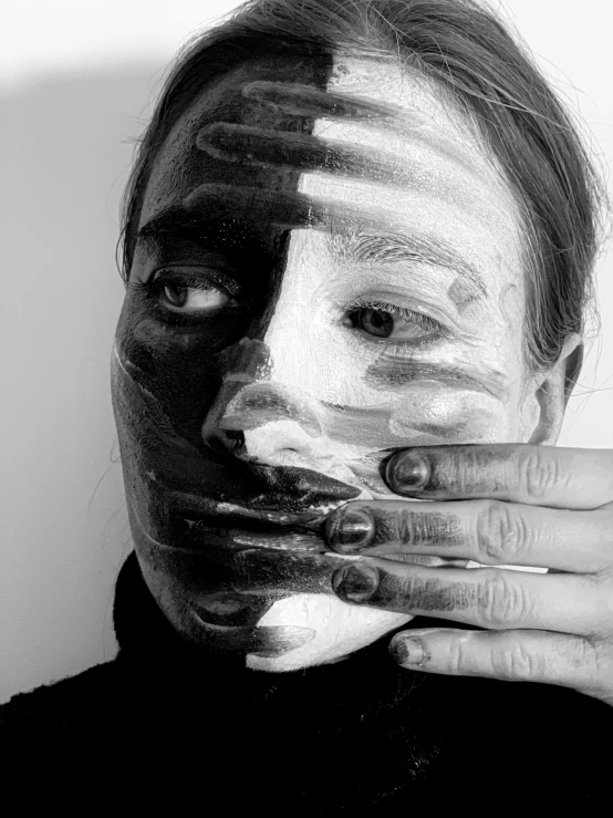 a black and white photo of a person with a painted face, a black and white photo, by Maria van Oosterwijk, hands shielding face, half and half, face mask, body paint