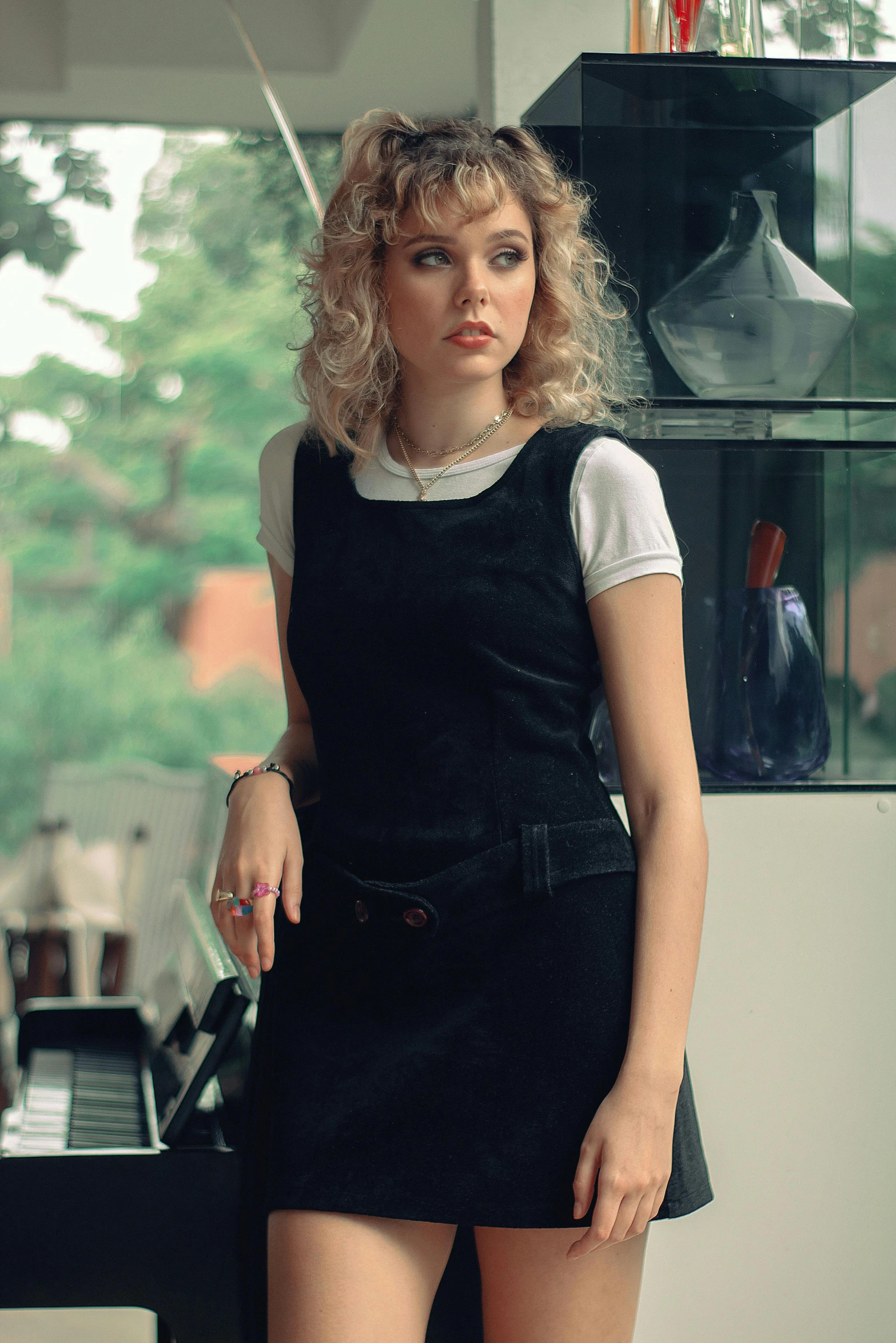 a woman standing next to a piano in a room, curly blonde hair | d & d, starbucks aprons and visors, fashion shoot 8k, gif