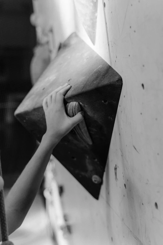 a black and white photo of a person climbing on a wall, uploaded, indoor, hands, cone