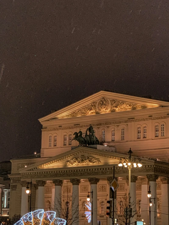 a large building with a clock on top of it, an album cover, inspired by Vasily Surikov, pexels contest winner, neoclassicism, snowfall at night, theater, 2 5 6 x 2 5 6 pixels, panorama