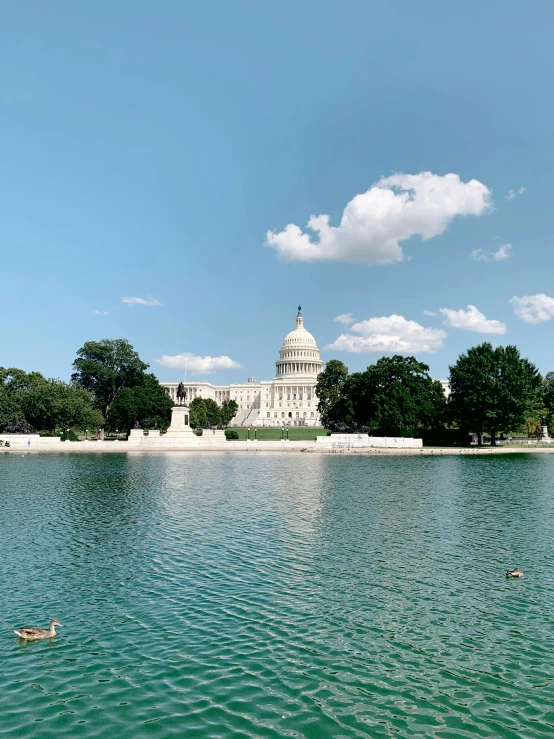 a large body of water with a building in the background, by Samuel Washington Weis, unsplash contest winner, neoclassicism, capitol hill, summer day, background image, 🚿🗝📝