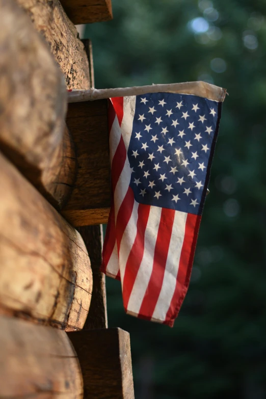 an american flag hanging from the side of a log cabin, a portrait, unsplash, closeup 4k, slide show, paul barson, camp