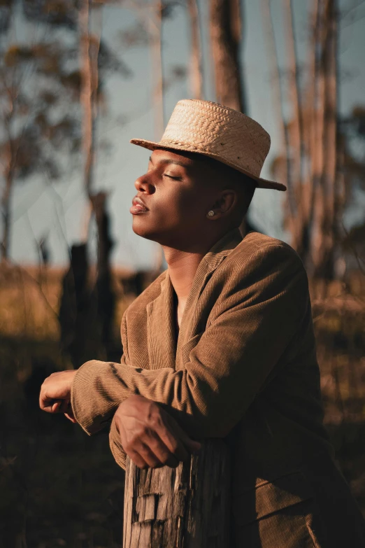 a man in a hat standing in the woods, an album cover, pexels contest winner, brown skinned, delicate androgynous prince, profile pose, sitting down