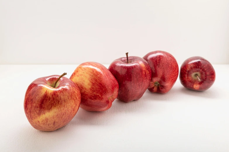 a group of apples sitting on top of a table, by Nina Hamnett, unsplash, photorealism, set against a white background, reds, 6 pack, side profile shot