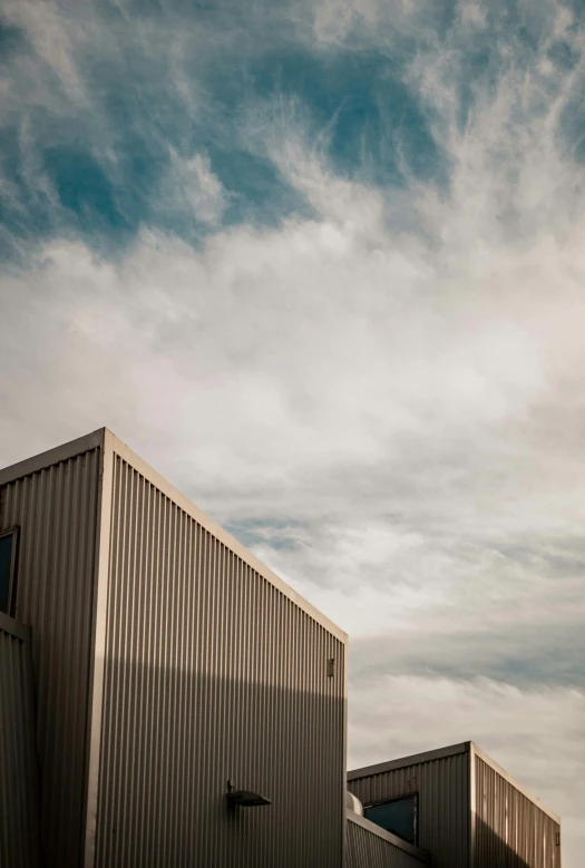 a man riding a snowboard on top of a snow covered slope, a picture, by David Simpson, unsplash, modernism, empty warehouse background, altostratus clouds, metal cladding wall, shipping containers