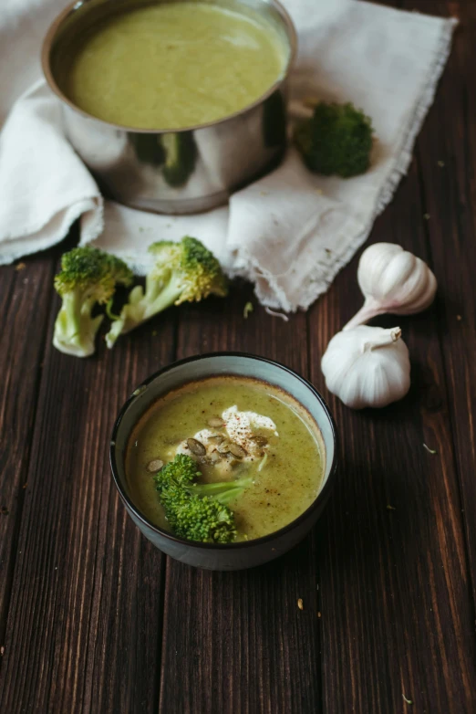 a bowl of soup sitting on top of a wooden table, broccoli, product image, grey, square