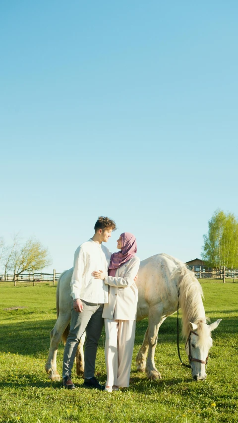 a man and a woman standing next to a white horse, a picture, by Basuki Abdullah, shutterstock, picnic, square, low quality photo, clear sky