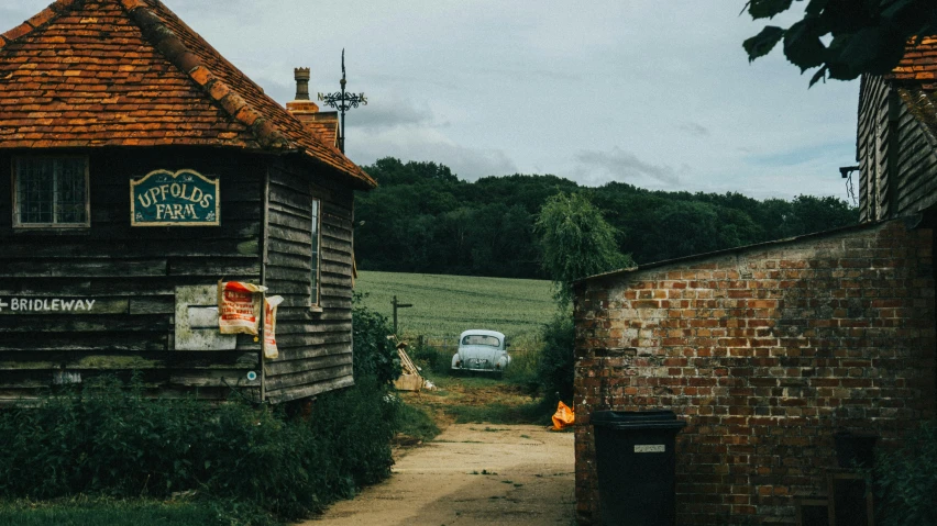 a couple of buildings that are next to each other, an album cover, by IAN SPRIGGS, pexels contest winner, outside in a farm, vintage car, madgwick, tiny village