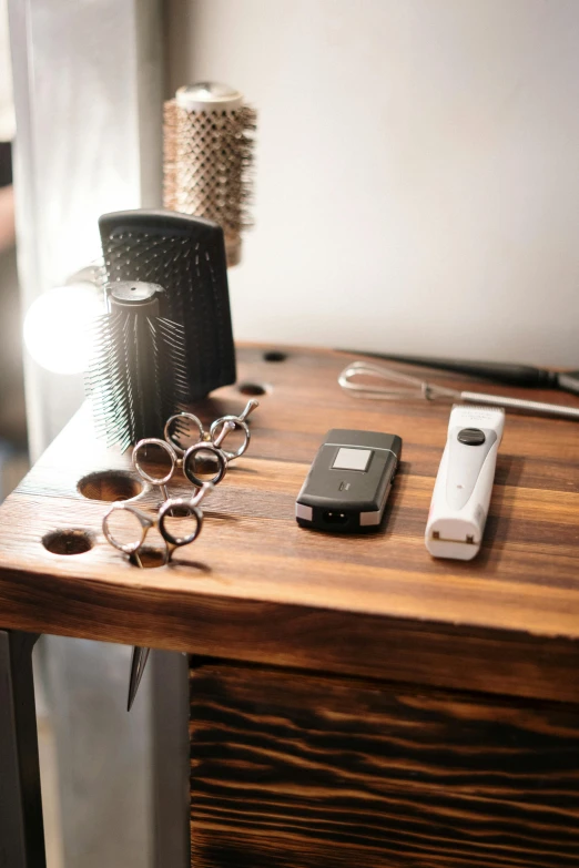 a cell phone sitting on top of a wooden table, table with microphones, blacksmith product design, kitchen counter, dwell