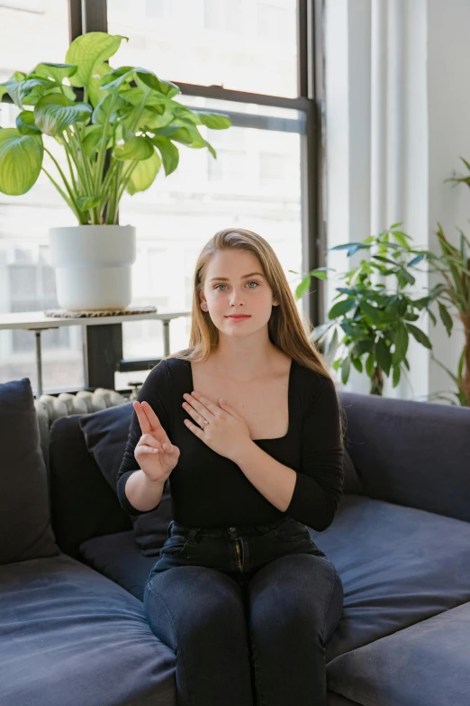 a woman sitting on top of a blue couch, by Julia Pishtar, unsplash, renaissance, hand gestures, model is wearing techtical vest, giving an interview, placed in a living room