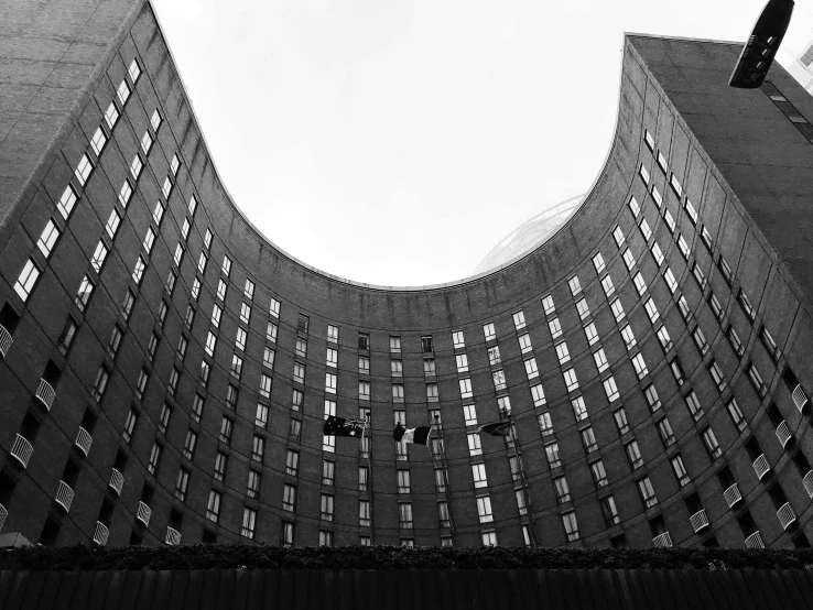 a black and white photo of a tall building, inspired by André Kertész, unsplash, brutalism, rounded roof, post - soviet courtyard, skycrapers, low dutch angle