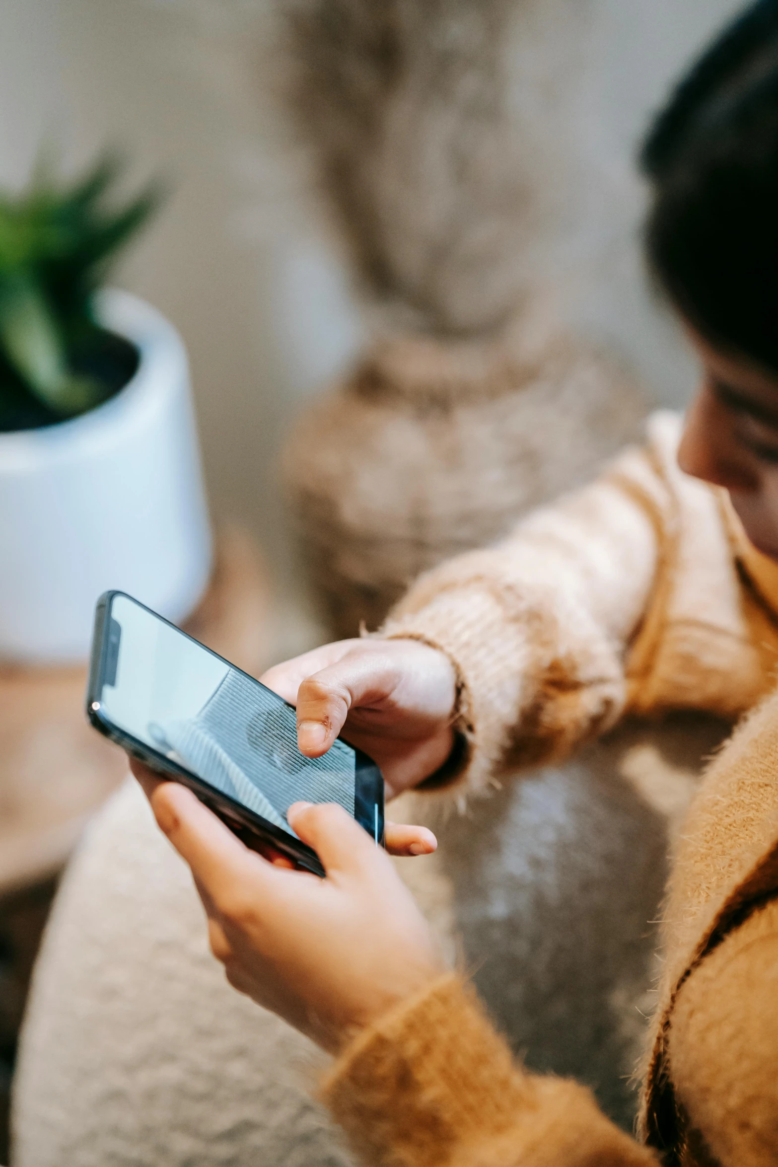 a woman sitting on a couch holding a cell phone, trending on pexels, corporate phone app icon, brown, sustainable materials, 1 2 9 7