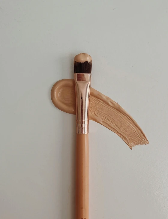 a close up of a brush on a white surface, by Robbie Trevino, ivory make up, shot with iphone 1 0, beige, copper