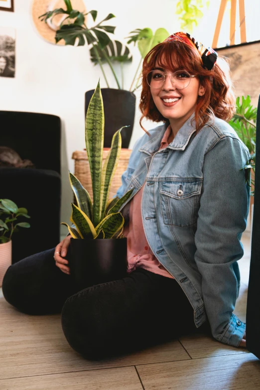 a woman sitting on the floor next to a suitcase, house plants, wearing a jeans jackets, alanis guillen, a redheaded young woman