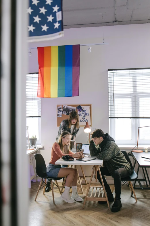 a couple of people sitting at a table in a room, trending on pexels, lgbt flag, standing in class, adafruit, college girls