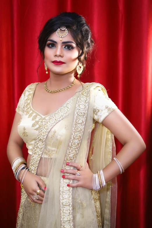a woman standing in front of a red curtain, inspired by Sudip Roy, with professional makeup, colors white!!, golden colour, dressed in a beautiful