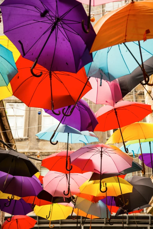 a bunch of colorful umbrellas hanging from the ceiling, out worldly colours, split near the left, rainny