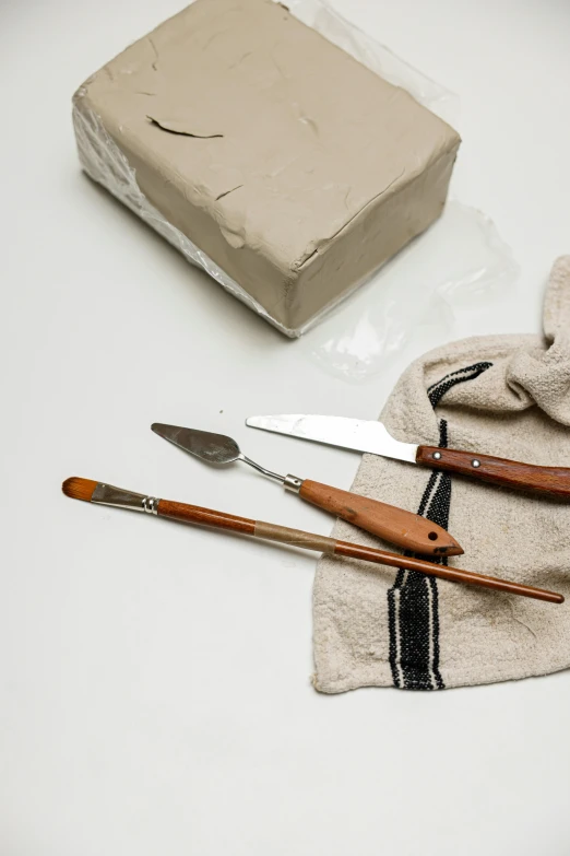 a couple of knives sitting on top of a table, a still life, inspired by Joseph Beuys, unsplash, detailed clay model, linen canvas, spatula, various sizes