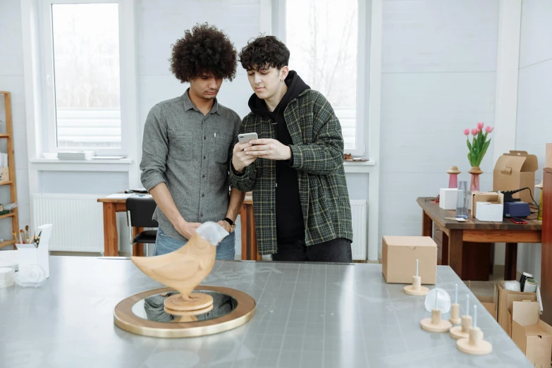 a couple of men standing next to each other in a room, pexels contest winner, kinetic art, scanning items with smartphone, tabletop model, college students, orrery