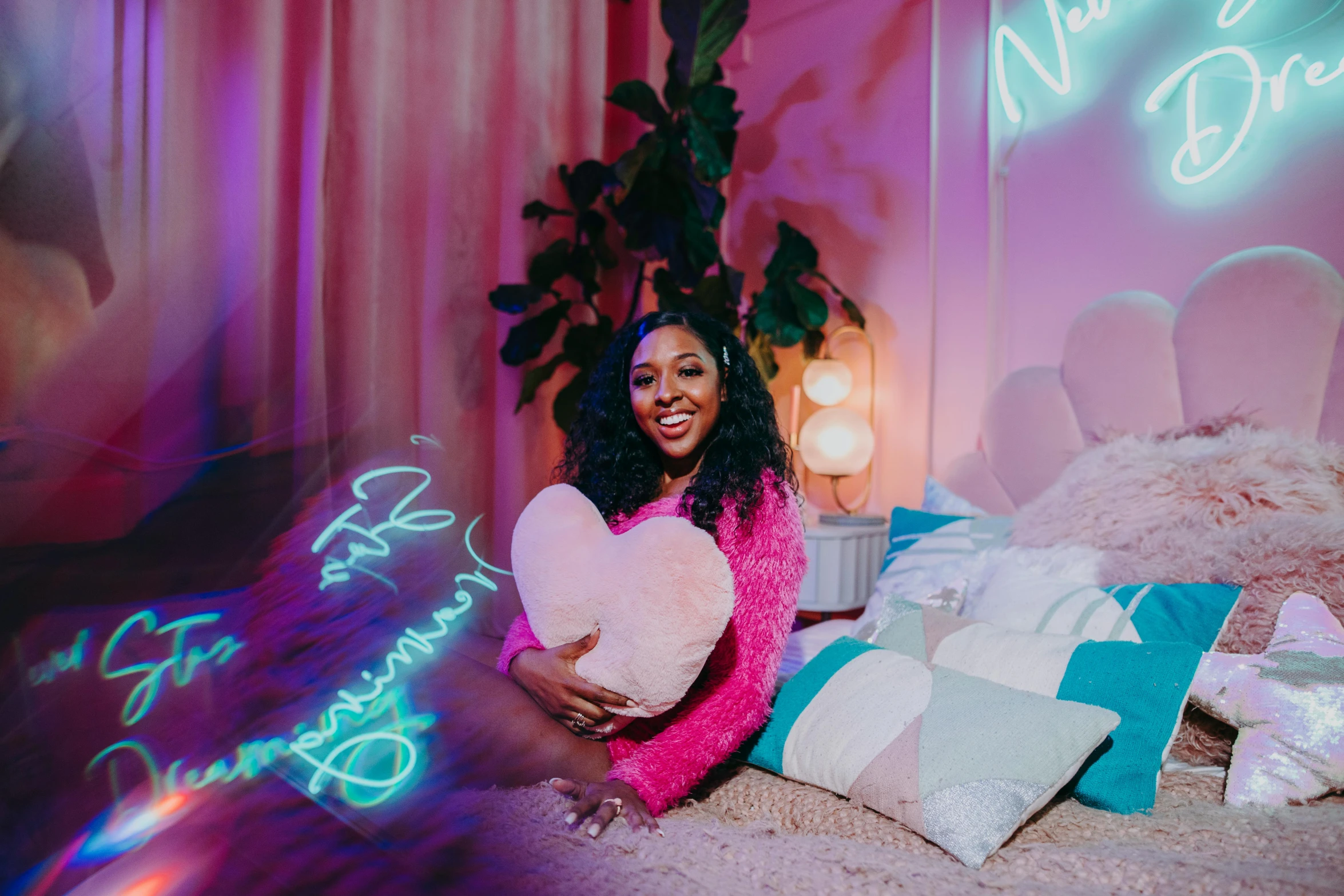 a woman sitting on top of a bed holding a pillow, trending on pexels, graffiti, pink neon lights, nicki minaj curvy, ☁🌪🌙👩🏾, product introduction photo