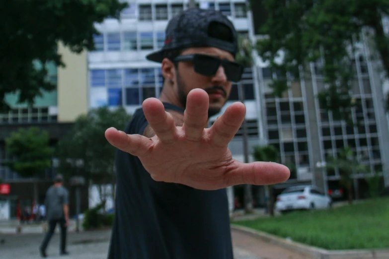 a man is making a stop sign with his hands, by Veno Pilon, pexels contest winner, hyperrealism, in sao paulo, avatar image, cardistry, wave a hand at the camera