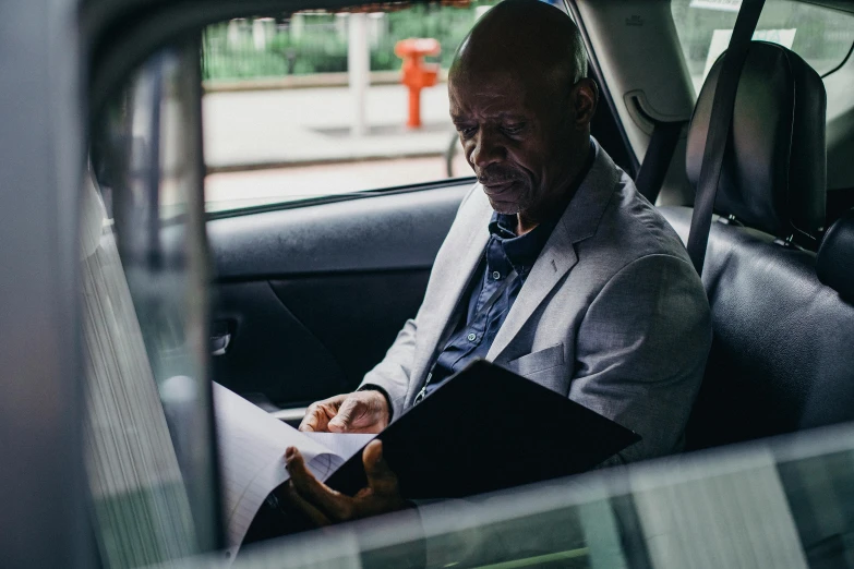 a man sitting in a car reading a piece of paper, mc ride, norman foster, profile image, profile photo