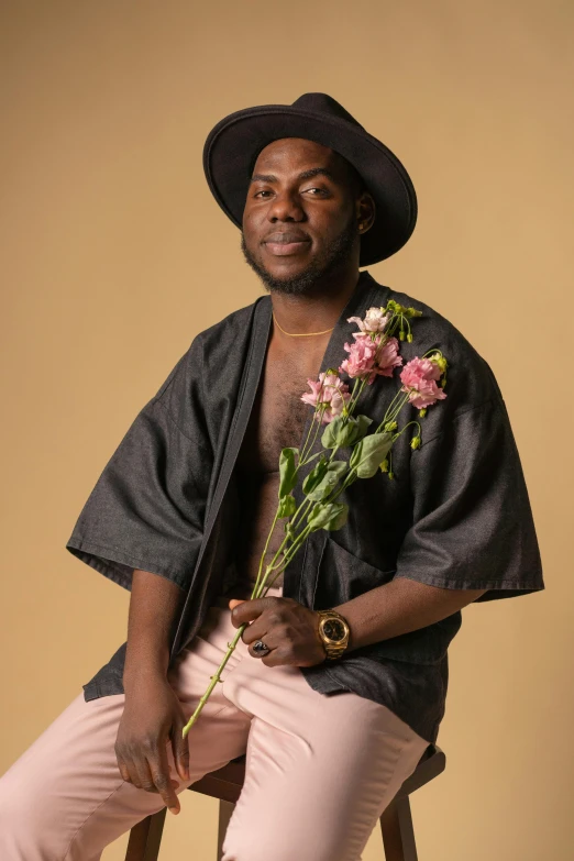 a man sitting on a stool holding a bunch of flowers, an album cover, by Jessie Alexandra Dick, trending on pexels, romanticism, man is with black skin, caracter with brown hat, roygbiv, casual pose