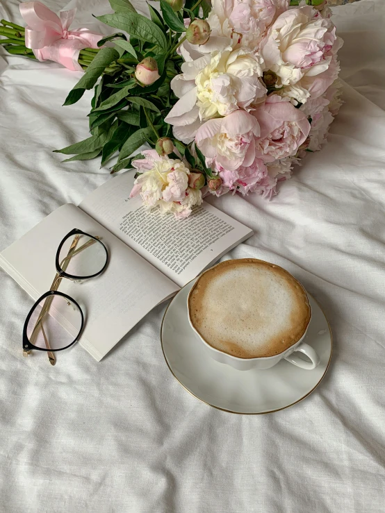 a cup of coffee and a book on a bed, by Lucia Peka, square rimmed glasses, promo image, blooming, high quality picture