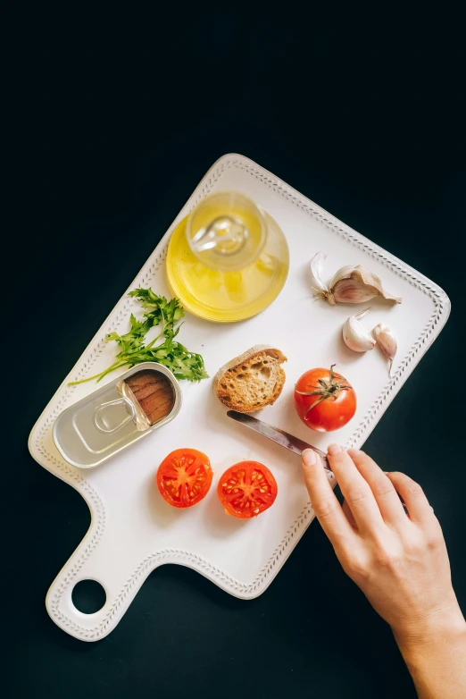 a person cutting tomatoes on a cutting board, by Adam Marczyński, plasticien, white, plating, olive oil, having a snack