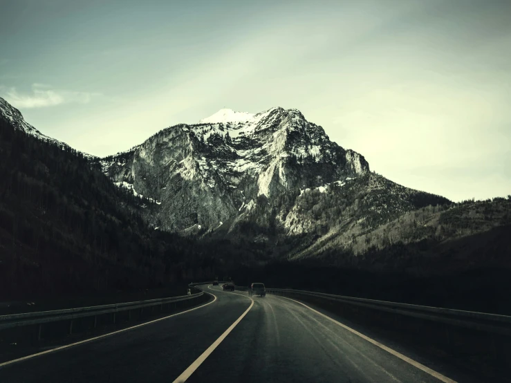 a long road with a mountain in the background, an album cover, by Karl Buesgen, unsplash contest winner, alessio albi, high traffic, medium format, grainy filter