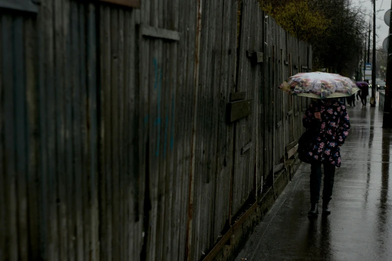 a woman walking down a street holding an umbrella, by Eamon Everall, waiting behind a wall, photographed for reuters, a wooden, thumbnail