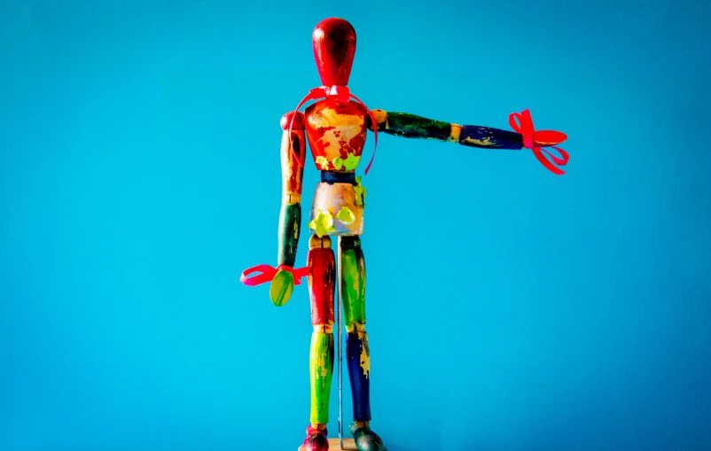 a wooden figurine holding a pair of scissors, by Sam Havadtoy, pexels contest winner, kinetic art, fully covered in colorful paint, full body hero, anorexic figure, man holding a balloon