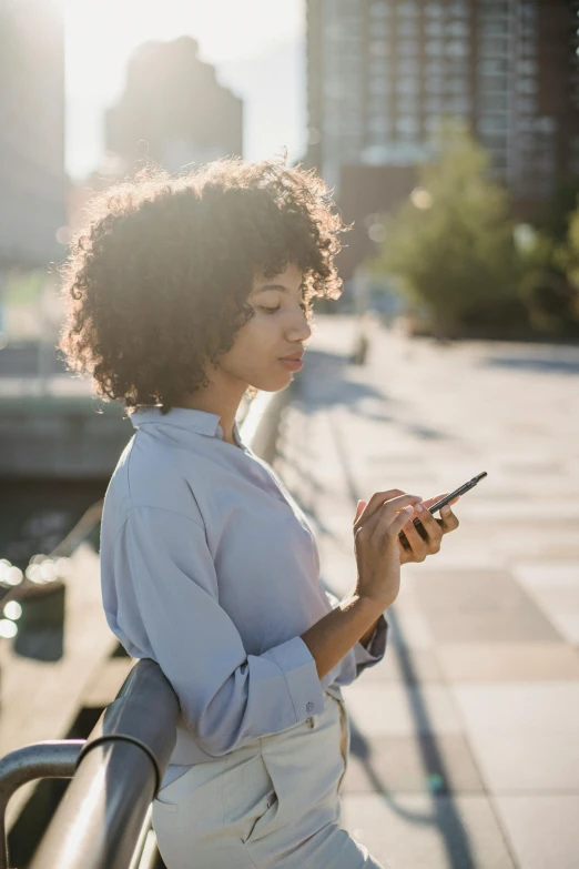 a woman standing on a bridge looking at her cell phone, trending on pexels, with afro, sunlit, your personal data avatar, looking distracted