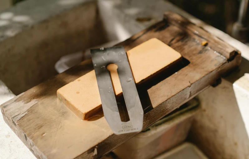 a piece of cheese sitting on top of a cutting board, by Bradley Walker Tomlin, mingei, holding wood saw, in a workshop, ochre, tungsten