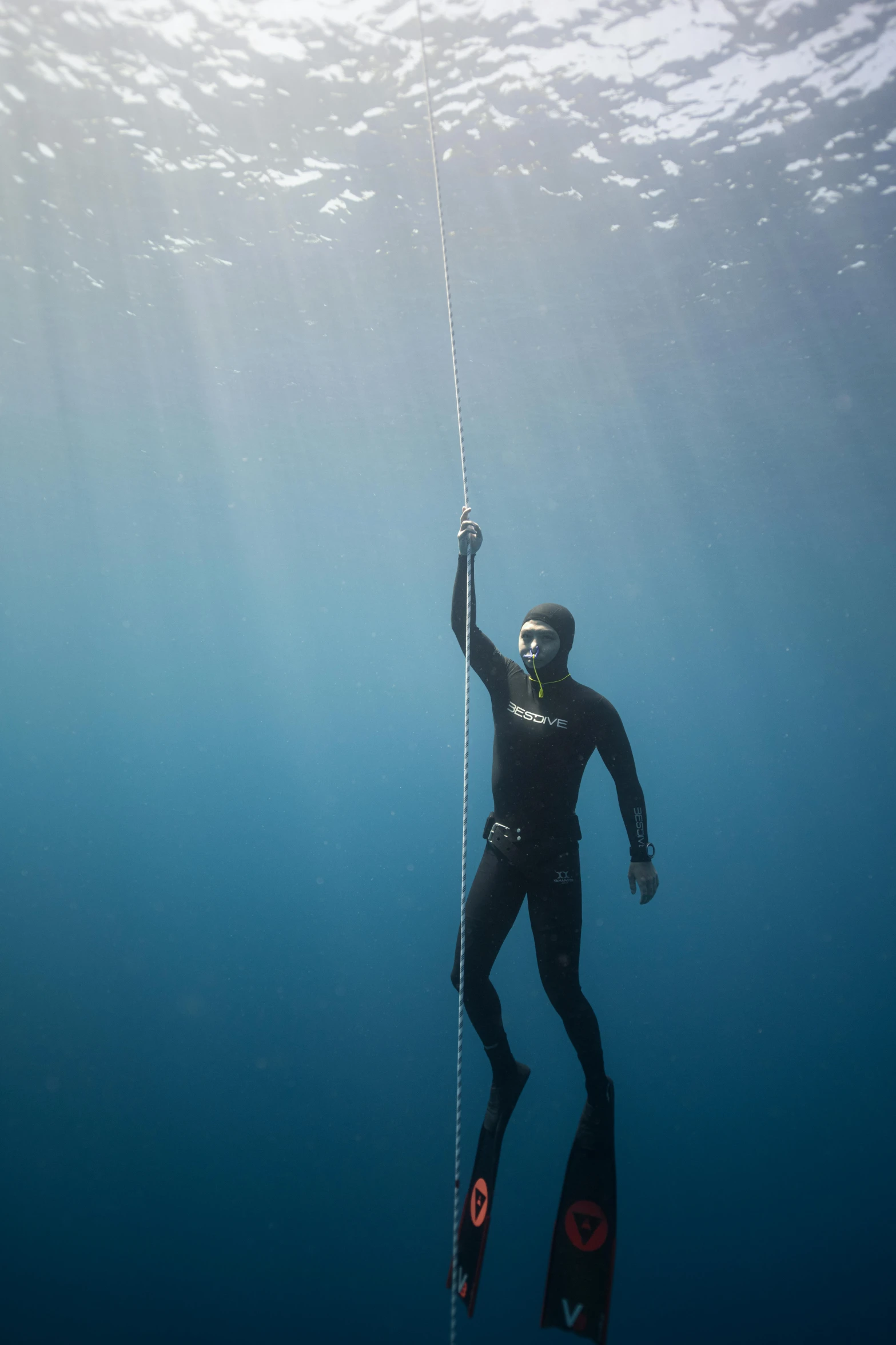 a man that is in the water with a rope, at the bottom of the ocean, black undersuit, sigma 55”, single figure