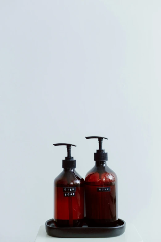 two bottles of liquid sitting on top of a counter, purism, brown:-2, soap, detailed product shot, small