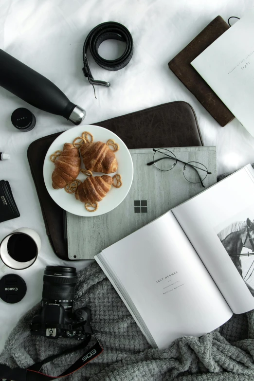 an open book sitting on top of a bed next to a cup of coffee, a still life, unsplash contest winner, items and gadget, hasselblad photo, food, black on white background