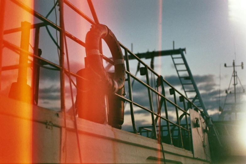 a man standing on top of a boat on a body of water, a polaroid photo, inspired by Elsa Bleda, unsplash, red lens flare, standing on ship deck, holga 120n, boat with lamp