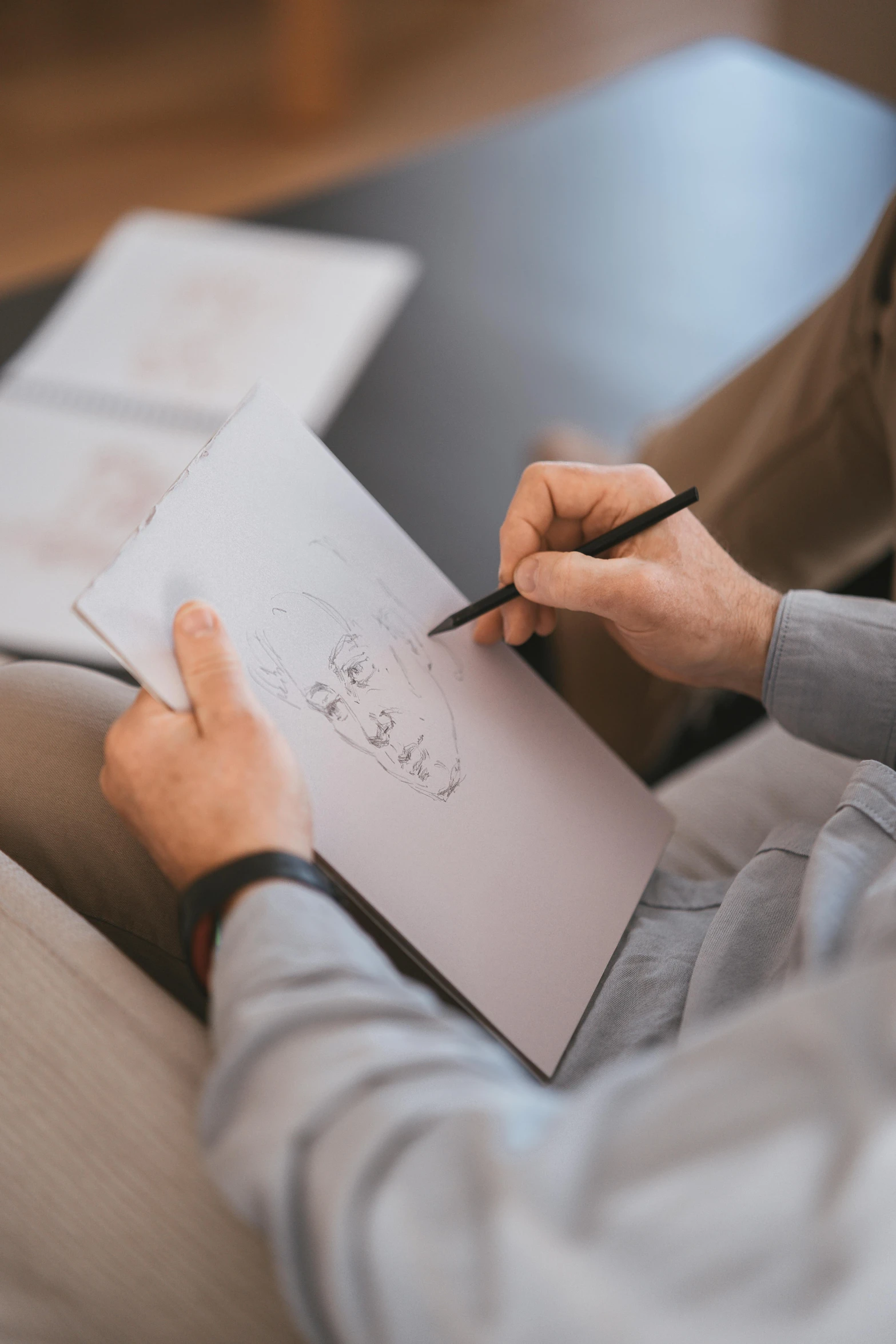 a man sitting on a couch writing on a piece of paper, a drawing, by Oskar Lüthy, pexels contest winner, product design concept, multiple stories, background image