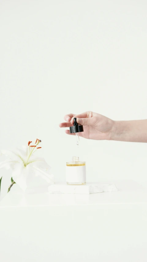 a woman standing next to a vase filled with flowers, unsplash, minimalism, droplets flow down the bottle, miniature product photo, dwell, apothecary