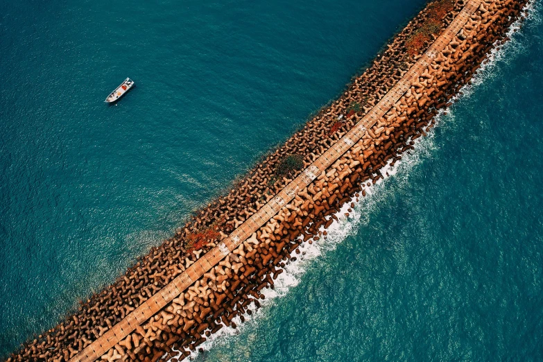 a large body of water with a boat in it, a tilt shift photo, by Ibrahim Kodra, pexels contest winner, fantastic realism, road to the sea, barriers, reefs, near a jetty