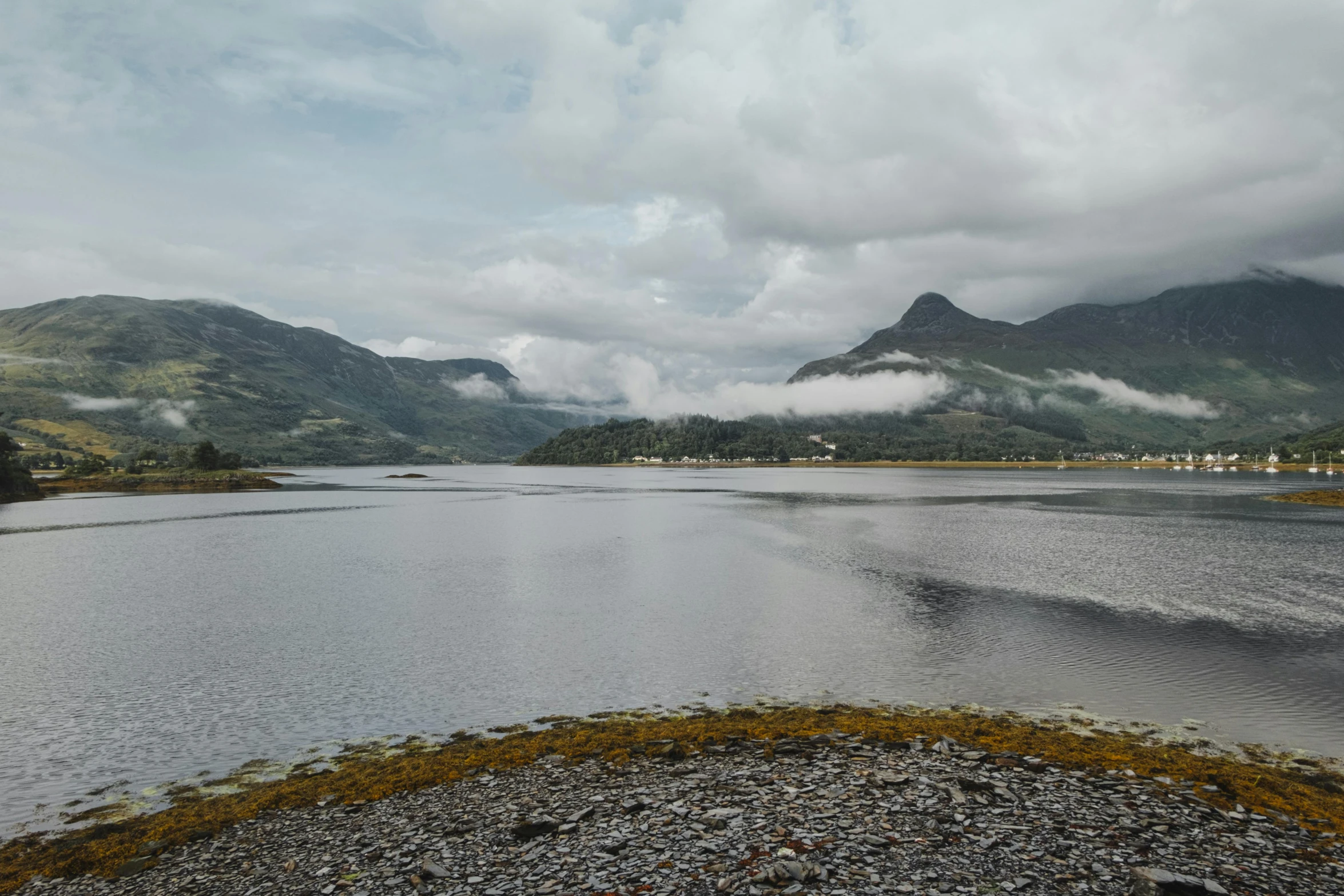 a body of water with mountains in the background, a picture, inspired by Oluf Høst, unsplash, hurufiyya, low clouds after rain, scottish, 2 0 0 0's photo, multiple stories