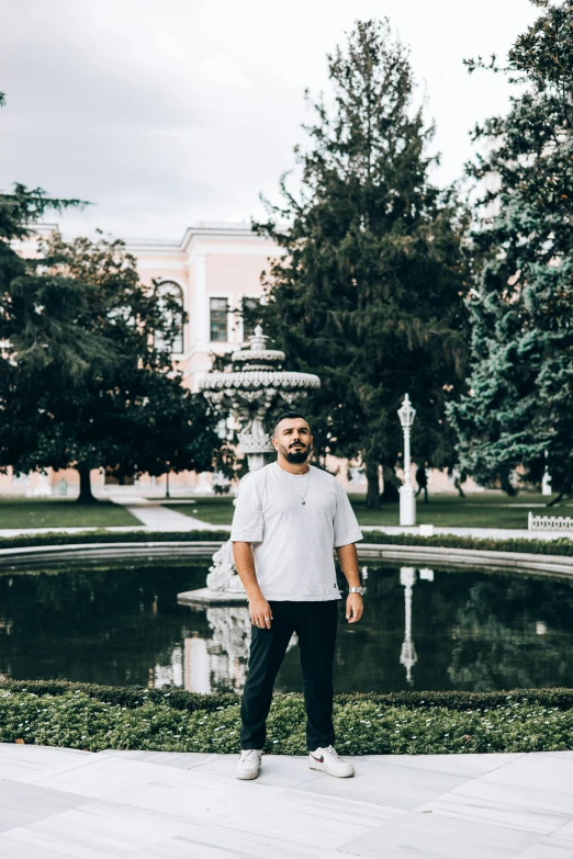 a man standing in front of a fountain, an album cover, pexels contest winner, azamat khairov, in a garden, high quality photo, thicc