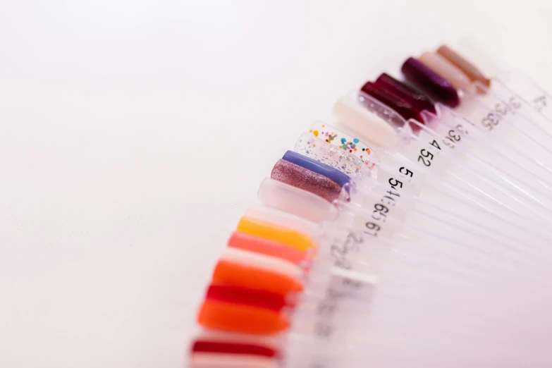 a row of nail polishes sitting on top of a white table, by Julian Allen, process art, pathology sample test tubes, shot from below, thumbnail, multi colour