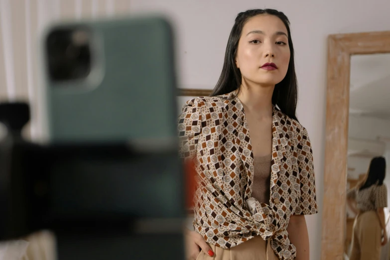 a woman taking a picture of herself in a mirror, trending on pexels, visual art, patterned clothing, gong li, in front of a computer, beige